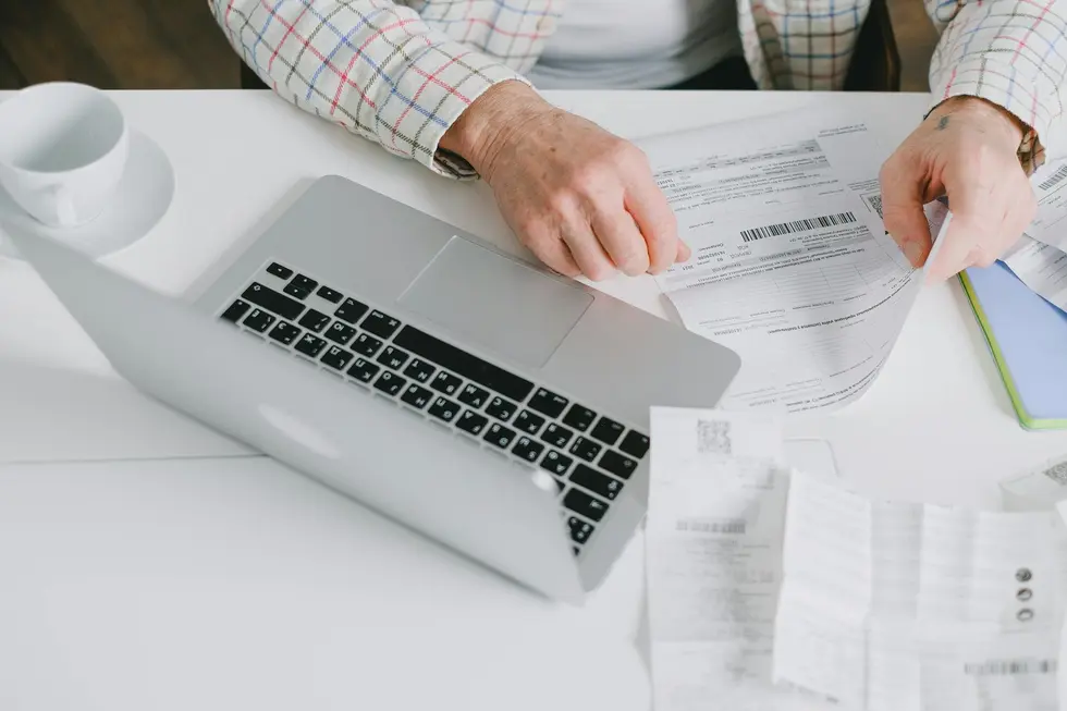 Pessoa analisando finanças com gráfico simples e comprovantes na cozinha