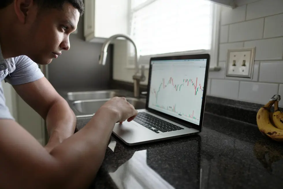 Pessoa estudando gráficos financeiros no laptop para melhorar o orçamento
