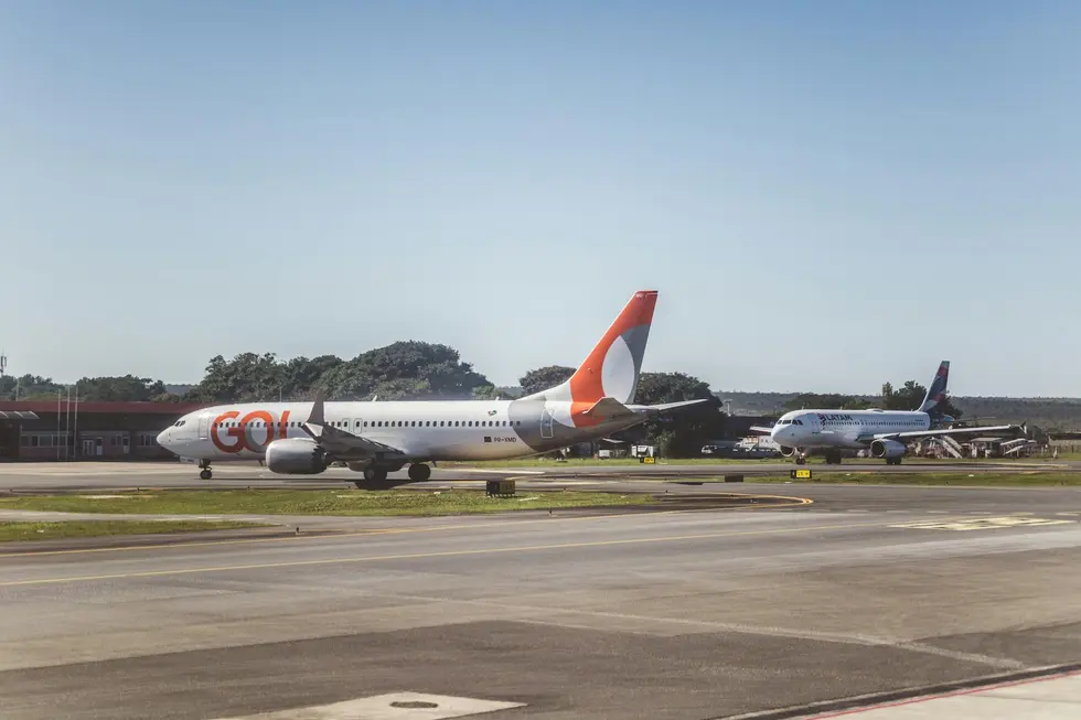 Pessoa com mala olhando avião decolar ao nascer do sol