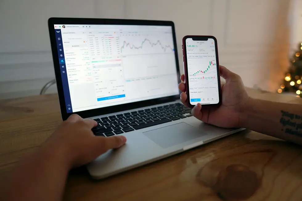 Computador e celular mostrando acompanhamentos financeiros no lar