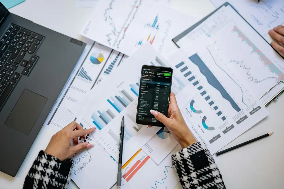 Celular e notebook com gráficos de orçamento doméstico automatizado na bancada da cozinha