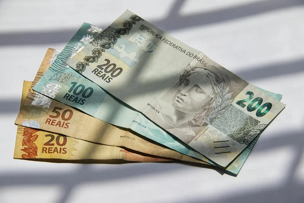 Moeda de Ethereum em cima de cédulas de real brasileiro