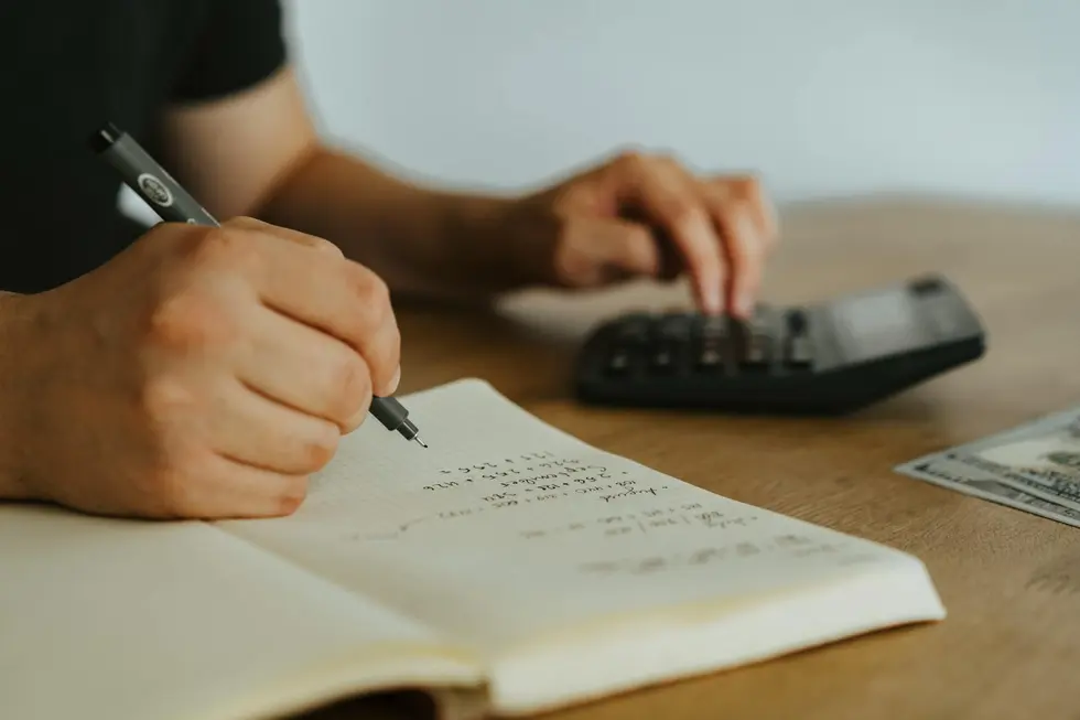 Mãos segurando Ethereum sobre caderno com cálculos de orçamento