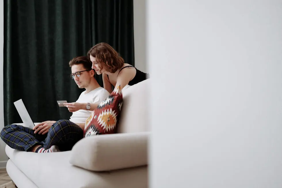 Casal feliz analisando economia e orçamento no computador em casa