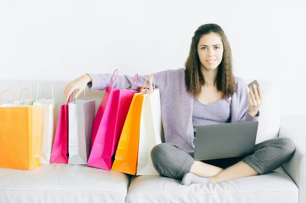 Família feliz consultando laptop com sacolas de compras ao redor