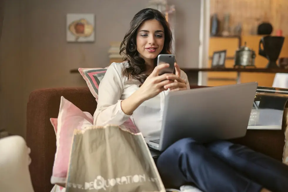 Mesa com dispositivos mostrando comparação de preços, família ao fundo