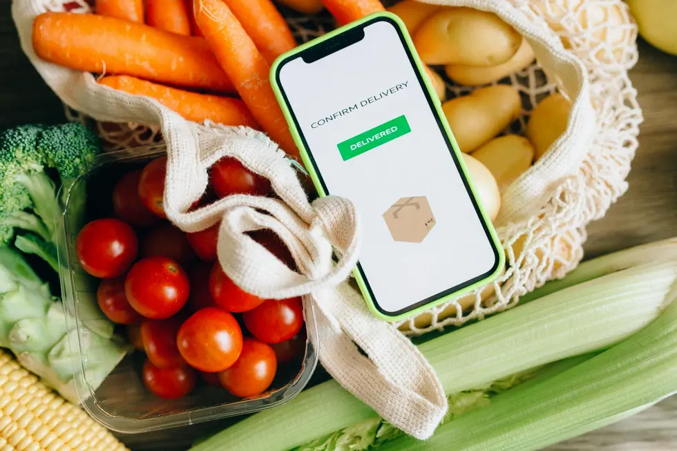 Mesa de cozinha com sacolas, recibos e smartphone mostrando comparação de preços