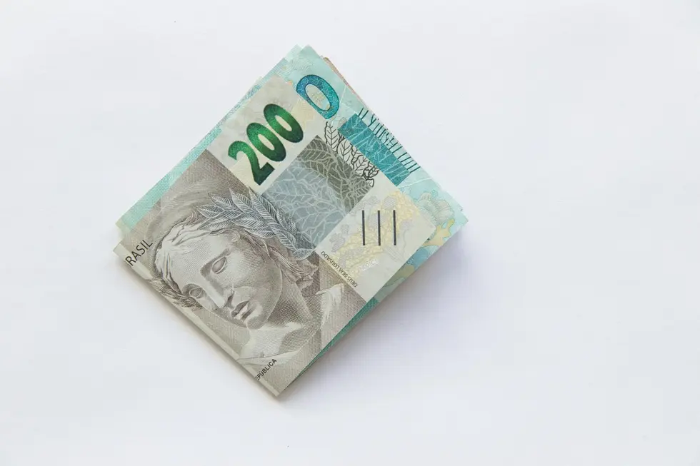 Notas de real e bilhetes da Mega-Sena sobre a mesa com família ao fundo