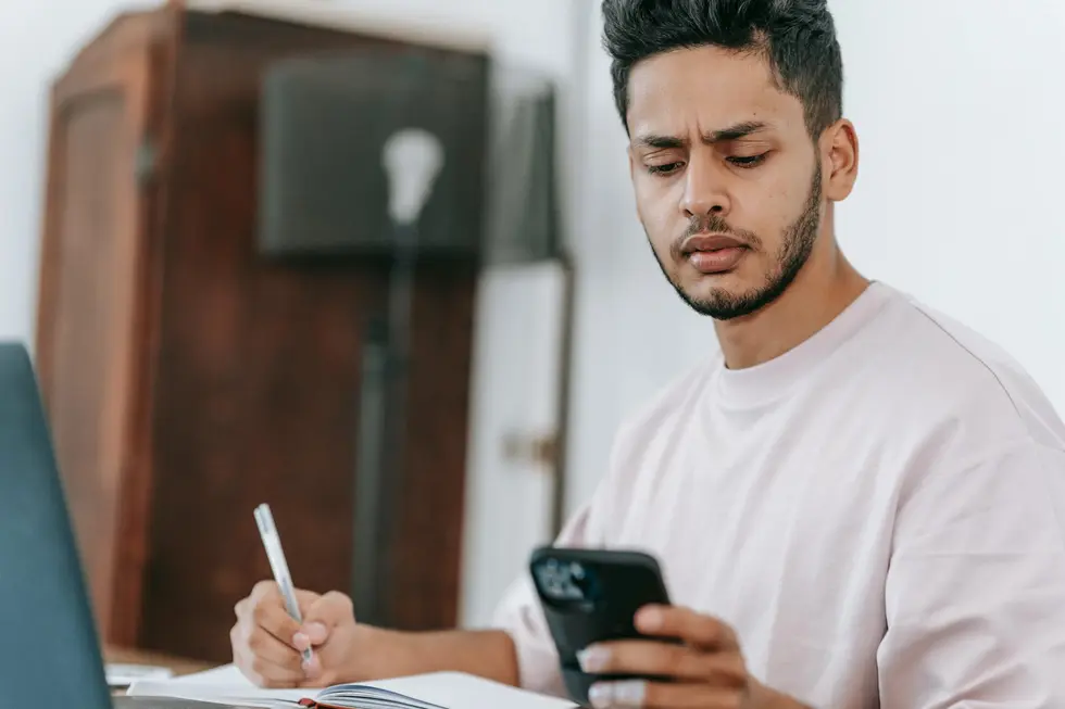 Pessoa consultando Quina no celular e anotando plano financeiro