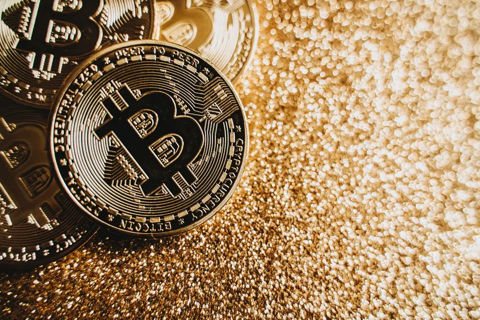 Moeda de Bitcoin sobre calculadora com pessoas ao fundo planejando as finanças