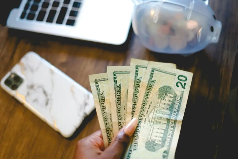 Família feliz ao redor de mesa com cartões, dinheiro e aparelhos mostrando dados financeiros