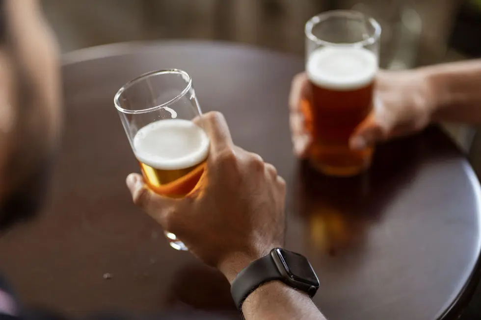 Mão segurando copo de cerveja artesanal em ambiente acolhedor