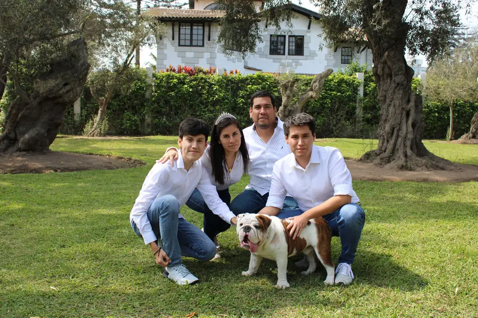 Família com cachorro em frente a casa moderna com carro