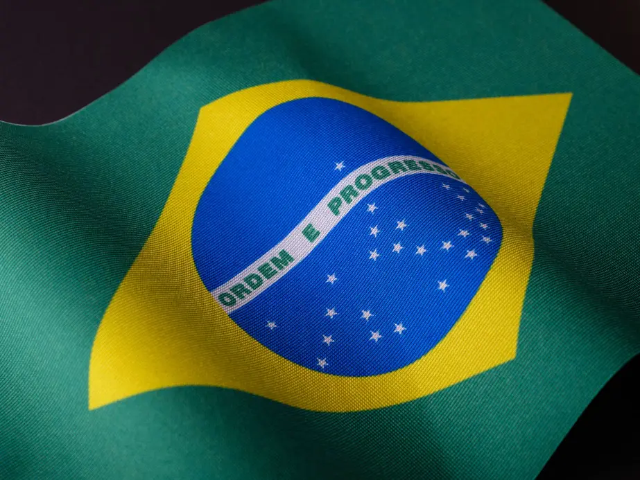 Símbolos do índice Dow Jones destacados sobre bandeira brasileira desfocada