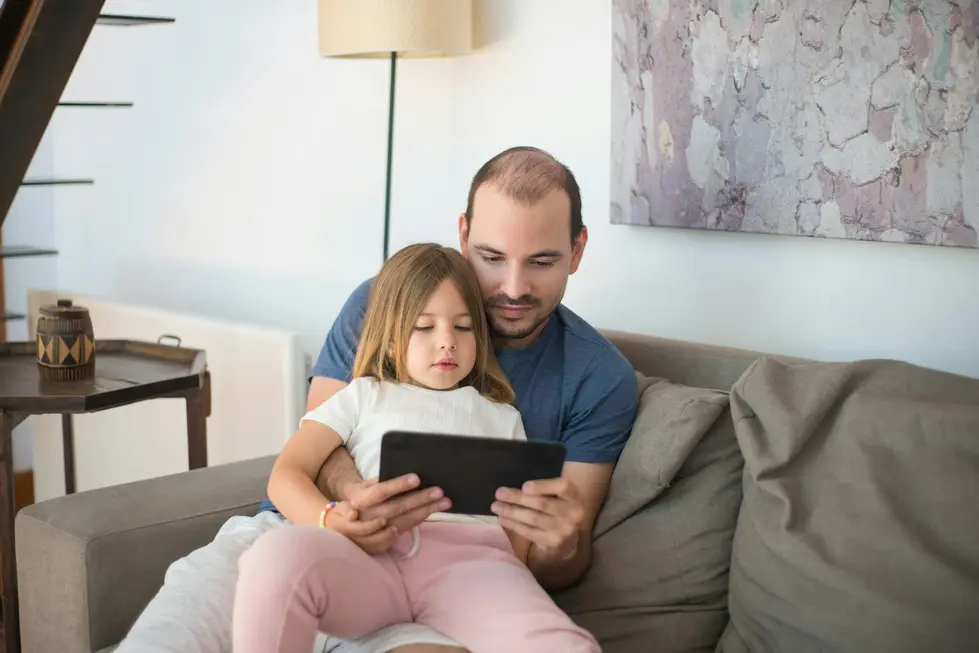 Família reunida analisando gastos com tablet exibindo logo do Itaú