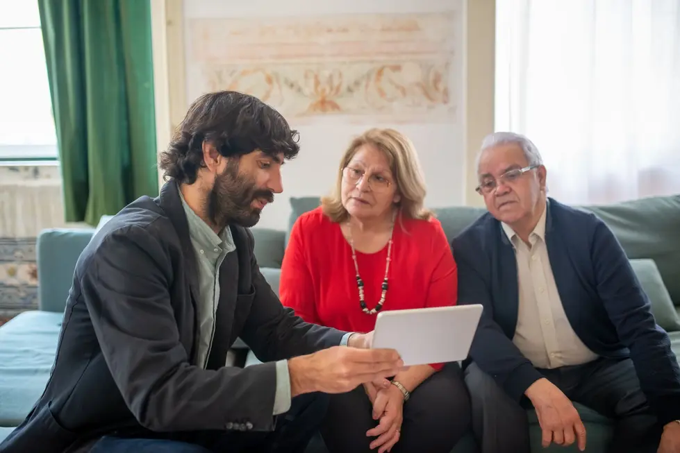 Família brasileira avaliando investimentos em casa com computador e gráficos
