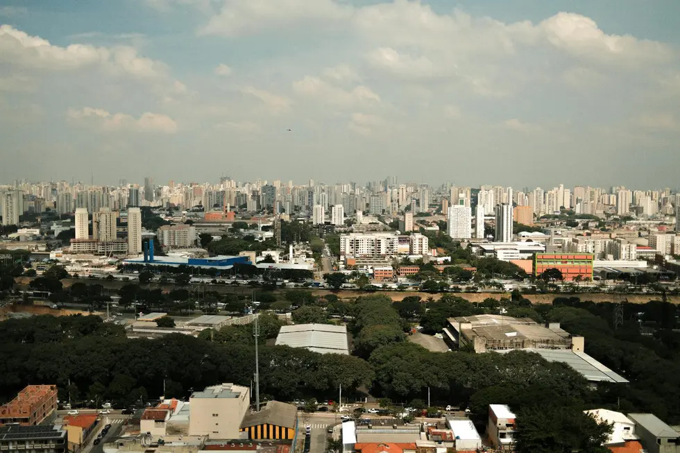 Pessoa sorrindo com bilhete da Mega-Sena diante da cidade