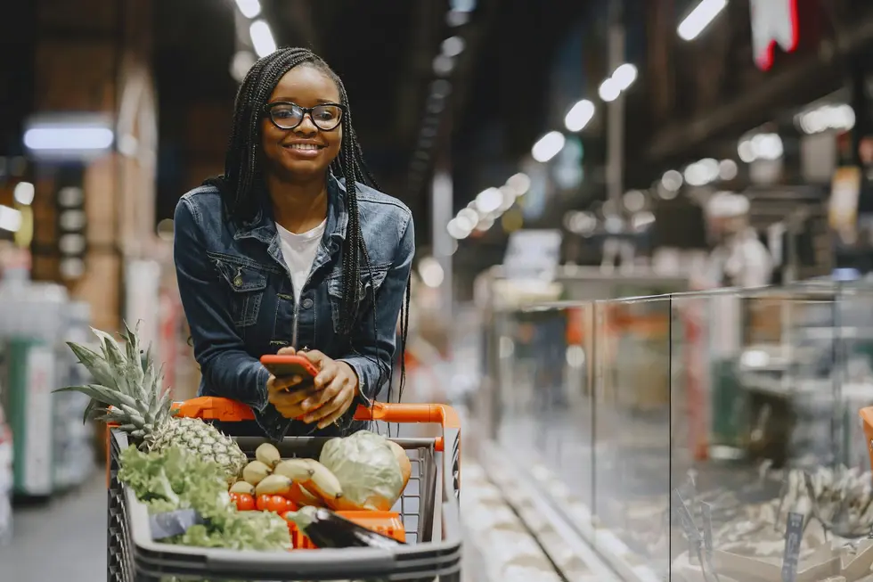 Mulher conferindo variações de preços pelo smartphone na cozinha